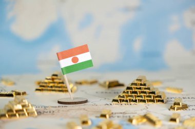 Minyatür bir Nijer ulusal bayrağı, ülkenin değerli maden kaynaklarını ve küresel ekonomik önemini görsel olarak tasvir eden bol miktarda altın külçesiyle çevrili ayrıntılı bir dünya haritasında yer alıyor.