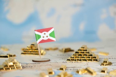 Burundi ulusal bayrağının yakın plan görüntüsü haritaya servetini, kaynak yönetimini ve finans piyasalarını temsil eden bir sürü altın külçesi yerleştirilmiş.