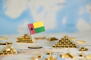 Gine-Bissau 'nun minyatür bir bayrağı, dünya haritasında ekonomik potansiyeli, kaynak değerini ve stratejik uluslararası mali duruşu resmeden sayısız altın külçeler arasında gururla duruyor.