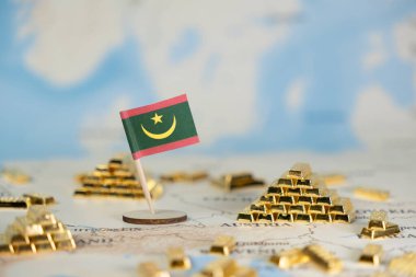 Mini Moritanya bayrağı, parıldayan altın külçeleri arasında ulusal ekonomik potansiyeli, küresel ticareti ve finansal istikrarı sembolize eden bulanık bir dünya haritasına yerleştirildi.