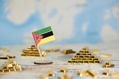 Küçük bir Mozambik bayrağı, ulusal kaynak zenginliği, küresel finans ve ekonomik yatırım olanaklarını temsil eden sayısız altın külçeleri arasında ayrıntılı bir dünya haritasında yer alıyor.