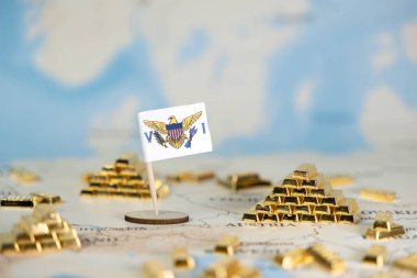 ABD Virjin Adaları 'nın minyatür bir bayrağı, uluslararası finans, offshore bankacılık ve ulusal varlık yönetimi tasvir eden sayısız altın külçenin yanındaki küresel bir haritada sergilenmektedir.