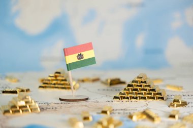 Bolivya bayrağı ve parlak altın külçeleri, uluslararası finans, ekonomik potansiyel, değerli maden kaynakları ve temiz kopya alanı gösteren bir dünya haritasına yerleştirilmiştir.