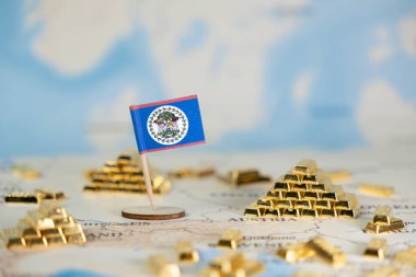 Belize 'nin küçük bir bayrağı, ulusal zenginlik, küresel finans ve yatırım potansiyelini temsil eden sayısız altın külçesiyle çevrili bir dünya haritasında yer almaktadır.