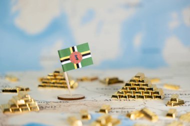 Dominica 'nın ulusal bayrağının bir dünya haritasında altın külçeleriyle birlikte görsel temsili, ülkenin ekonomisini, uluslararası ticaretini ve değerli mali varlıklarını simgeliyor