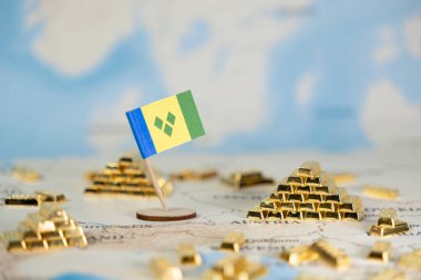 Saint Vincent ve Grenadines 'in bayrakları, ulusal ekonomik büyüme, kaynak yönetimi ve küresel yatırımı sembolize eden dağınık altın külçeli bir dünya haritasına yerleştirildi.