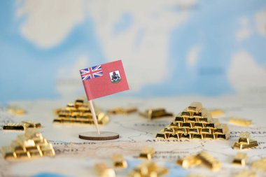 Küçük Bermuda bayrağı, uluslararası finansmanı, offshore yatırım stratejilerini ve refah yönetimini gösteren küresel bir harita üzerinde duruyor.