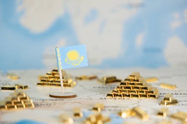 Bir dünya haritasında Kazakistan bayrağı ve altın külçelerine yakın plan, ulusal ekonomik kalkınmayı, değerli metal rezervlerini ve geniş alana sahip küresel yatırım olanaklarını sembolize ediyor