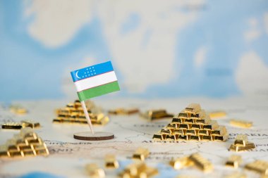 Ülkenin değerli maden kaynakları, mali istikrar ve uluslararası ticaret potansiyelini kavramlaştıran, bir haritada parlak altın külçelerin yanına asılmış minyatür Özbekistan bayrağı