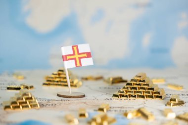 Guernsey bayrağının kapatılması ve küresel haritada altın külçeleri istiflenmesi, mali güvenlik, uluslararası zenginlik yönetimi, offshore yatırım stratejileri ve küresel ekonomik istikrarın vurgulanması