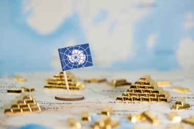 Bir Antarktika bayrağı, dağınık altın külçeleri yakınlarındaki bir dünya haritasında kıta kaynaklarının zenginliğini, ekonomik potansiyelini ve önemli çevresel koruma sorunlarını sembolize ediyor.