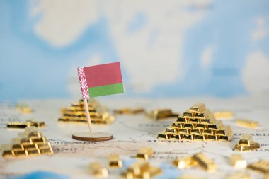Belarus 'un minyatür bir bayrağı, ulusal ekonomik refah ve küresel finans kavramlarını gösteren birden fazla altın külçesinin etrafa saçıldığı bir dünya haritasında belirgin bir şekilde sergilenmektedir.