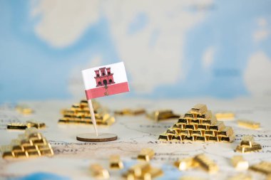 Uluslararası zenginliği, stratejik finansal planlamayı ve ekonomik refahı temsil eden, dünya haritasında sayısız altın külçeli Cebelitarık bayrağına odaklanmış bir yakın plan.