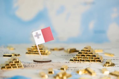 Bir dünya haritasında Malta bayrağı ve altın külçelerinin yakın çekimi, Malta 'nın finansal gücünü, uluslararası ticaretini ve refahını, geniş gökyüzü arkaplan kopyalama alanını temsil ediyor