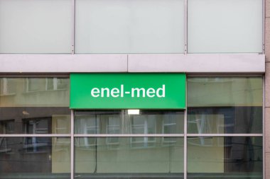 Poznan, Polonya - 30 Nisan 2025: Modern bina, sağlık hizmetlerini gösteren, yansıtıcı pencereler ve parlak bir Enel-medikal tabela içeriyor