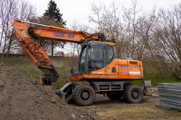 Poznan, Polonya - 30 Nisan 2025: Toprak taşıma ve kalkınma için hazırlanan, açık hava şantiyesindeki çamurlu zemine yerleştirilmiş büyük turuncu mobil kazıcı