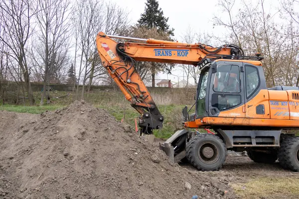Poznan, Polonya - 30 Nisan 2025: Endüstriyel turuncu tekerlekli bir kazıcı büyük bir toprak yığınının yanında duruyor.