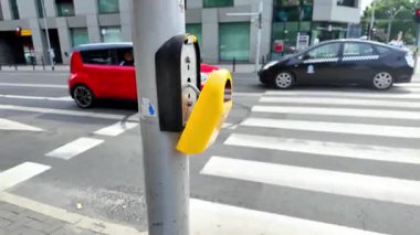 Kırık sarı yaya geçidi düğmesini gri bir direkte tasvir eden kentsel bir sahne, ihmal edilen şehir altyapısını ve kamu hizmetlerinin acilen onarılması gereğini vurguluyor