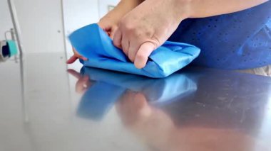 Profesyonel ellerin titizlikle katlanmış mavi dokumasız kumaş, muhtemelen tıbbi aletleri sterilize etmek için, sağlık güvenliği ve hastane hijyen prosedürlerini vurgulamak için.