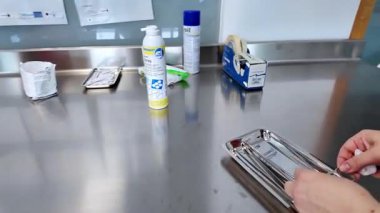 İnsan elleri steril metal tepside, hijyen ve klinik kullanıma özenle hazırlanan özel tıbbi gereçler düzenler.