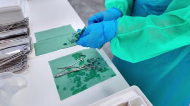 Islak yeşil mendille yeniden kullanılabilir tıbbi aletleri temizleyen bir sağlık görevlisinin eldivenli ellerine yakın plan, hijyen ve hasta bakımını vurgulayan