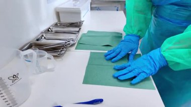 Eldivenli eller steril yeşil perdeleri temiz beyaz bir tezgahın üzerinde, tıbbi işlemler veya laboratuvar çalışmaları için sağlam hijyen ve güvenliği gösteren aletlerle hazırlarlar.