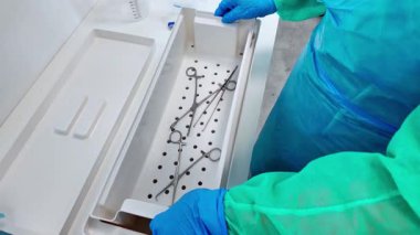 Dezenfeksiyon çözeltisine batırılmış klemp ve makas gibi çeşitli cerrahi aletlerin yakın görüntüsü, sağlık ortamlarında steril uygulamaları vurguluyor