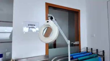 Temiz, modern bir laboratuvarda ayarlanabilir bir kolu olan beyaz bir büyüteç, bilimsel araştırma, hassasiyet ve tıbbi doğruluk kavramlarını vurguluyor.