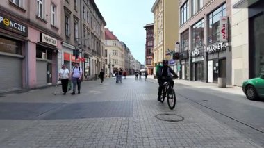 Poznan, Polonya - 1 Haziran 2025: Canlı şehir sahnesi, kaldırım taşı caddesinde ilerleyen birçok yayanın MAX Market ve Ponczek gibi ticari mağazaların önünden geçişini içeriyor.