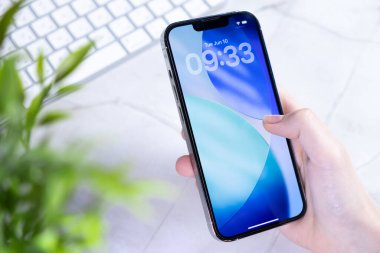 Poznan, Polonya - 10 Haziran 2025: En son iOS 26 kilit ekranı ve Sıvı Cam tasarımı ile yeni Apple iPhone 'unu tutan bir elin yakın çekimi