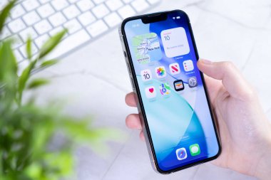 Poznan, Polonya - 10 Haziran 2025: Gelişmiş bir Apple iPhone 'u elinde tutan, Yeni iOS 26' yı sergileyen ve modern bir çalışma alanında tasarım konusunda çarpıcı bir Sıvı Cam