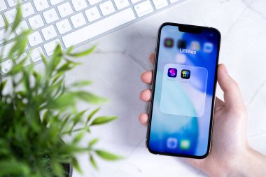 Poznan, Polonya - 10 Haziran 2025: Yeni iOS 26 Sıvı Cam Tasarım Uygulamaları içeren kamu hizmetleri klasörünün yer aldığı çağdaş bir akıllı telefonu yakın plan