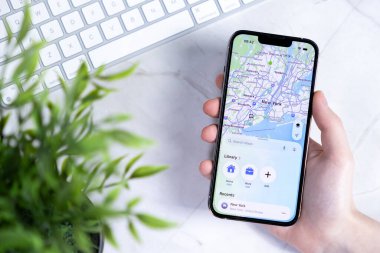 Poznan, Polonya - 10 Haziran 2025: Yeni iOS 26 ve Sıvı Cam tasarımlı modern bir akıllı telefon, gelişmiş navigasyon için detaylı New York haritasını gösteriyor