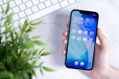 Poznan, Polonya - 10 Haziran 2025: Bir el dijital bağlantı için Sıvı Cam Tasarımı ile yeni IOS 26 işletim sistemini gösteren modern bir akıllı telefonu tutuyor