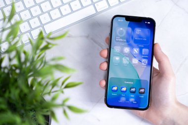 Poznan, Polonya - 10 Haziran 2025: Kişiselleştirilebilir arayüzlü Sıvı Cam Tasarımı içeren iOS 26 'yı gösteren yeni bir akıllı telefon ile etkileşime giren bir elin yakın çekimi