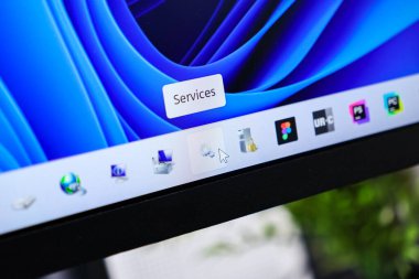 Poznan, Polonya - 6 Haziran 2025: Bir görev çubuğundaki bir uygulama simgesinin üzerinde gezinen bir fare imlecinin yakın çekimi, 'Hizmetler' araç ipucunu ortaya çıkarıyor, sistem kontrolü ve dijital işlemleri gösteriyor