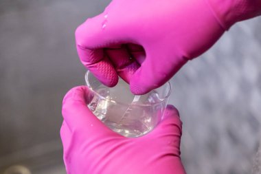 Eldivenli ellerin temiz bir bardakta şerit ile çok önemli bir su arıtma testi yaparak sağIık için konut duş sisteminden optimum filtrelemeyi sağlaması.