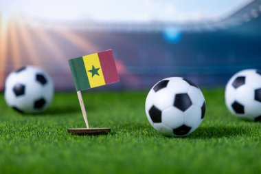 Senegal 'in ulusal bayraklı minyatürünün yakından görüntüsü suni yeşil sahada futbol toplarının yanında, atletik rekabeti temsil ediyor ve ulusal gururu kopya alanla temsil ediyor.