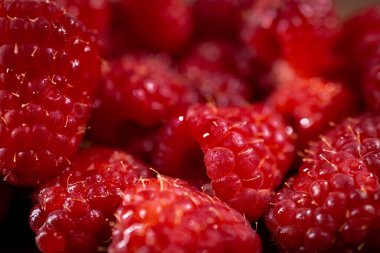 Taze, olgun kırmızı ahududu kümesinin detaylı makro fotoğrafı yiyecek ve içecek kavramları için doğal tatlılıklarını ve besin değerlerini vurguluyor.