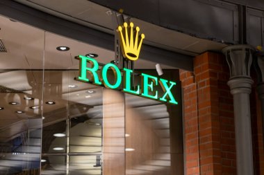 Poznan, Polonya - 30 Haziran 2025: Aydınlatılmış yeşil Rolex tabelası, prestiji temsil eden modern bir lüks saat mağazasında belirgin bir şekilde sergileniyordu.