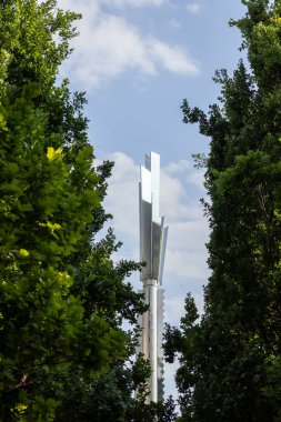 Poznan, Polonya - 18 Haziran 2025: Geometrik şekilli uzun metal Stela Heinza Macka heykeli, yeşil ağaçlar ve mavi gökyüzü arasında, kentsel sanat ve tasarım kavramları için