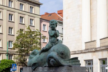 Poznan, Polonya - 18 Haziran 2025: Yıpranmış bronz bir heykelin yakın çekimi, yunusa binen bir melek heykelinin, yeşil patinajlı yaşlı bir şehir çeşmesinin