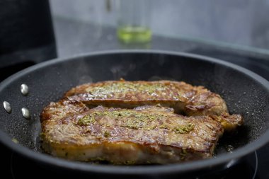 İki leziz bifteğin yakın çekim görüntüsü taze biberiyeyle pişirilmiş ve yapışmaz tavada, yemek blogları, sağlıklı tarif siteleri veya mutfak içeriği için mükemmel.