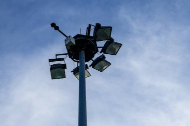 Verimli geniş ölçekli dış mekan aydınlatma ve güvenlik altyapısı için tasarlanmış birkaç güçlü LED projektörlü sağlam bir direğin yukarı bakış açısı