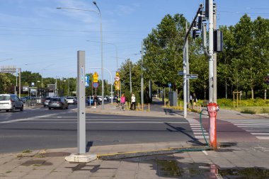 Poznan, Polonya - 26 Haziran 2025: AQUANET elektrik direği ve Droga Debinska 'da su sızdıran kırmızı bir yangın musluğu,