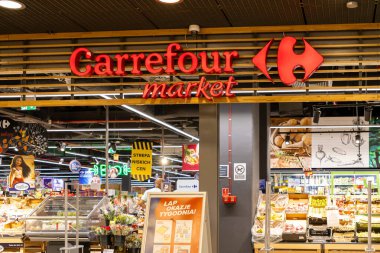 Poznan, Polonya - 26 Haziran 2025: Aydınlatılmış Carrefour piyasa tabelası modern perakende mağaza girişini süslüyor, taze yiyecek sergiliyor, günlük alışverişçiler için vitrinler açıyor