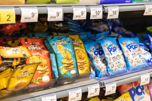 Poznan, Polonya - 26 Haziran 2025: Crisp bruschetta ve tatlı patlamış mısır gibi çeşitli paketlenmiş yiyeceklerin tüketici seçimi için yoğun bir süpermarket rafında canlı gösterimi