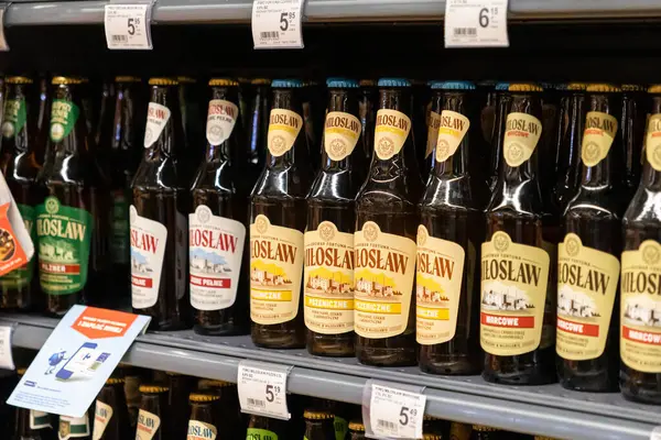 Poznan, Polonya - 26 Haziran 2025: Sıralar dolusu Miloslaw ve çeşitli etiketli Fortuna bira şişeleri bir süpermarket rafında, perakende satış için hazır bir şekilde sergilenmektedir