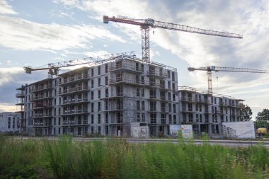 Poznan, Polonya - 13 Temmuz 2025: Konut binasının inşaat halindeki beton iskeleti, Gran ve POTAIN vinçleri modern kentsel genişlemeyi simgeliyor
