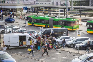 Poznan, Polonya - 13 Temmuz 2025: Dinamik sahne, merkezi bir taşıma kavşağında şehir hareketliliğini ve altyapısını vurgulayan çok sayıda kişiyi ve farklı araçları gösteriyor